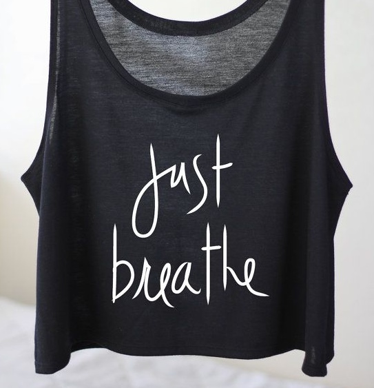 A black vest with the words "Just breath" in white curly text on the front